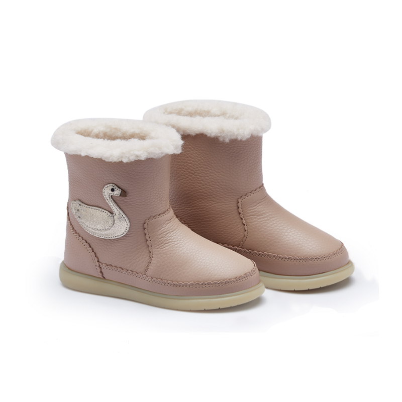 A pair of toddler ankle boots in a dusty pink color, featuring a white wool lining at the top, a white swan applique on the side, and a light beige sole.