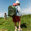 boy walks with a friend in a meadow wearing his state bags kane kids double pocket backpack in olive diagonal zipper