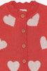 Red cardigan with white heart patterns and buttons