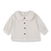 A baby girl's cream-colored linen blouse with a ruffled Peter Pan collar and three brown buttons